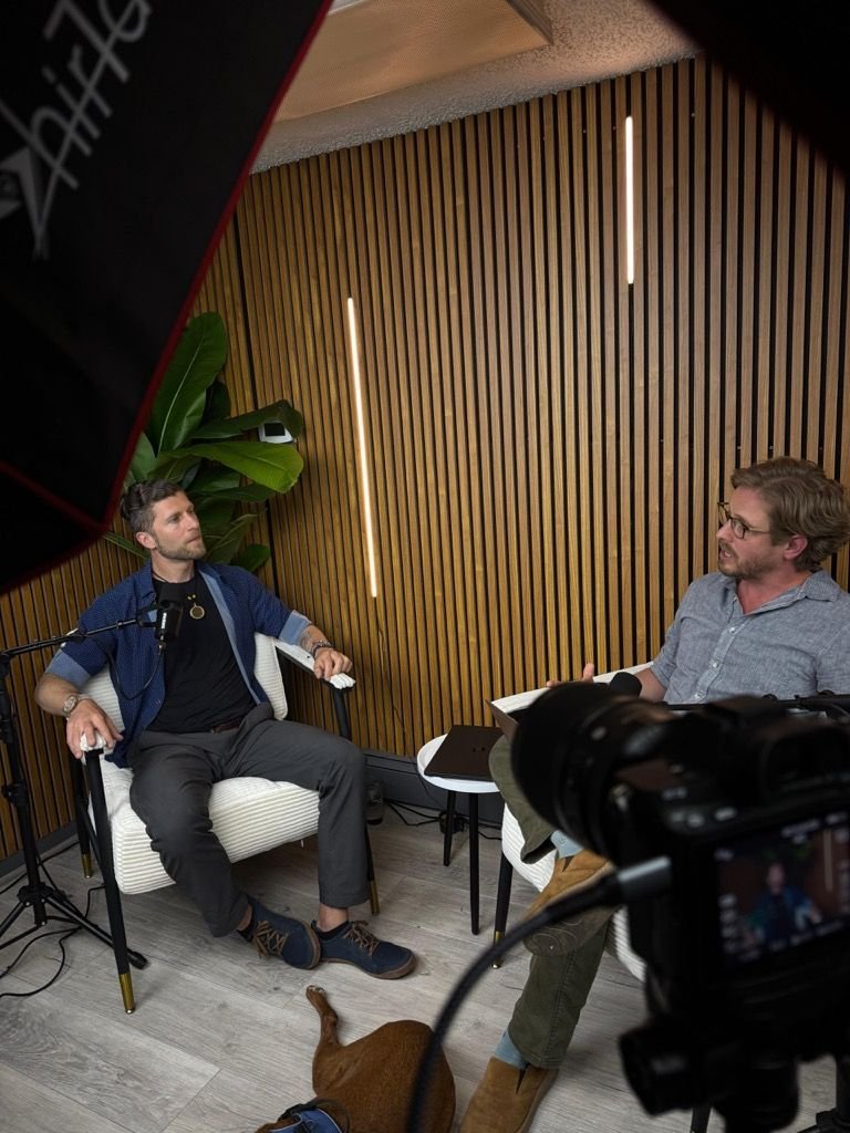 Julian being interviewed in a professional studio — Sailor the dog at his feet
