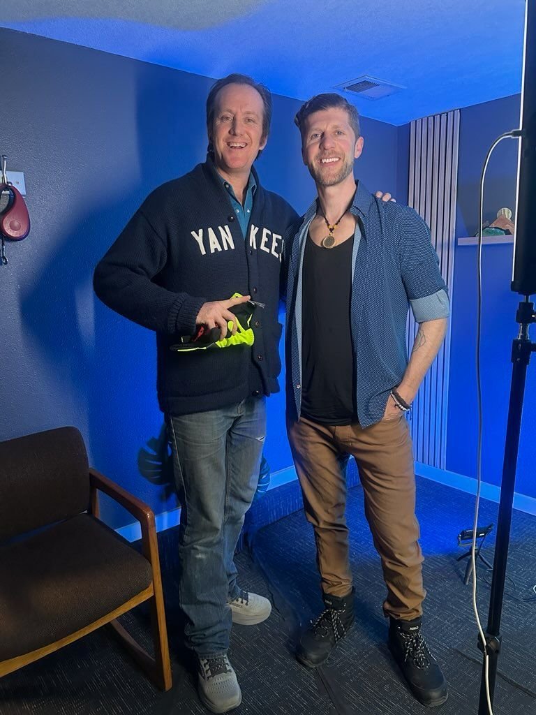 Julian with a podcast guest in a blue studio